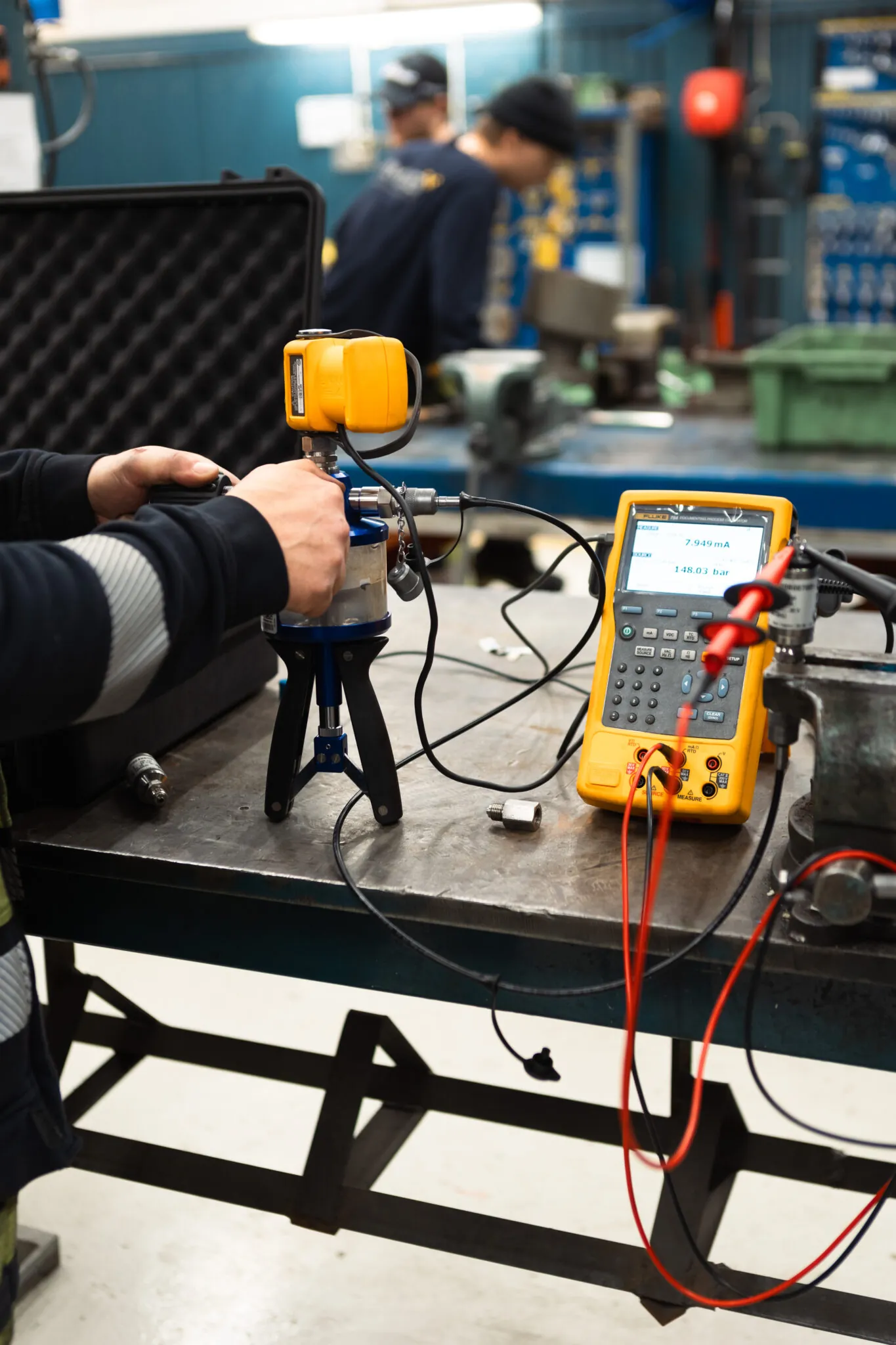 Ventiltekniker kalibrerar precisionsventil med gul testdator som visar tryckvärden på displayen