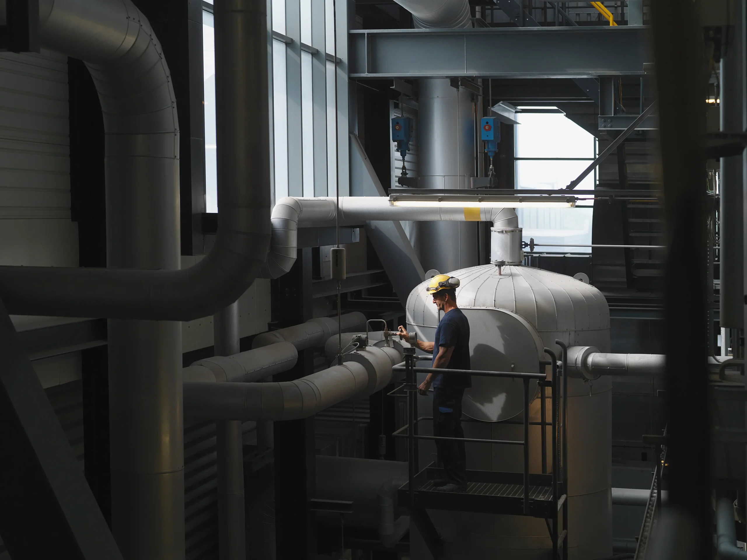 Ventiltekniker med hjälm och skyddsglasögon utför funktionskontroll på rörledningar i processindustrianläggning
