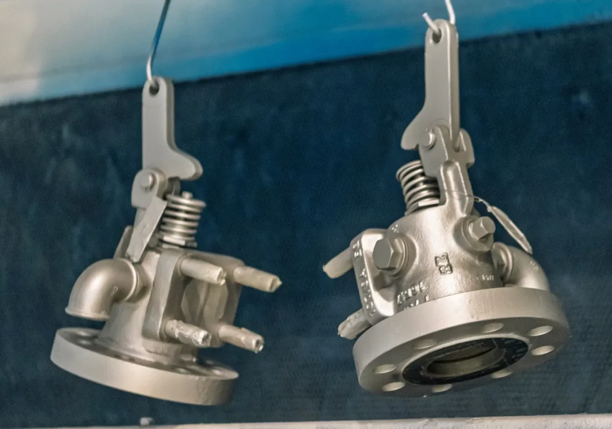 Två säkerhetsventiler hängande för ytbehandling – renovering av ventildelar i VIMAB:s verkstad